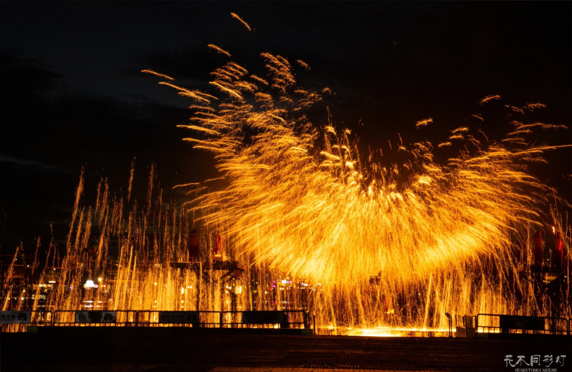 铜官窑古镇夜景全景，打铁花表演作为视觉焦点，与古镇建筑灯光秀相互辉映。